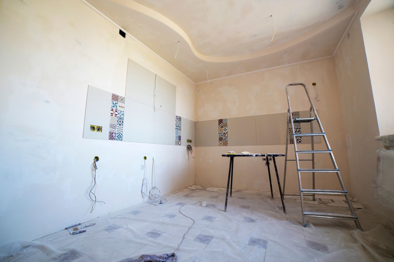 services-04 Interior view of a room under renovation with paint, tiles, and tools.
