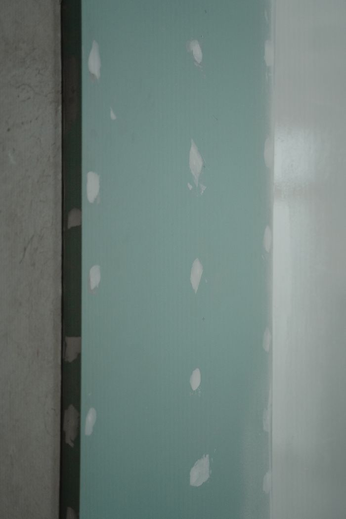 services-03 Freshly installed green drywall with white patches, ready for painting or finishing touches in home renovation.